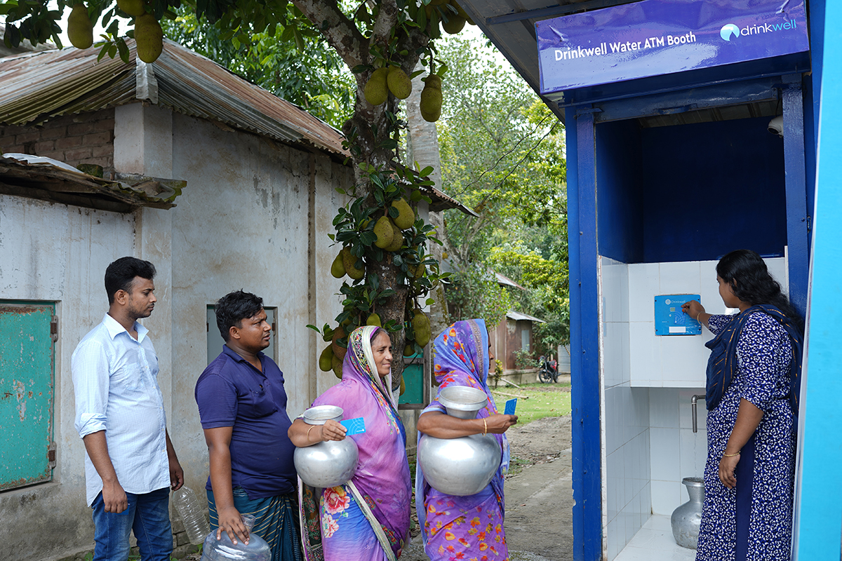 Bangladeshi men and women line up to get clean drinking water from a DrinkWell ATM Booth