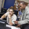 two african american men talking over a computer